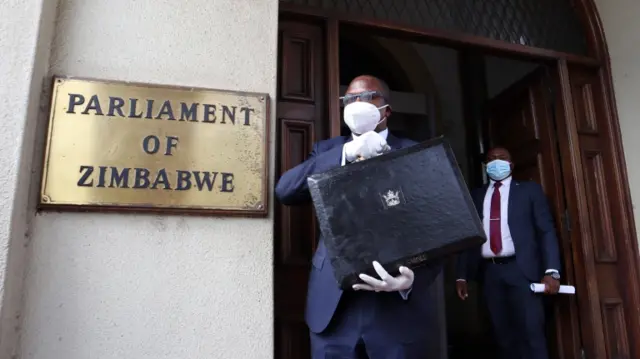 Zimbabwe's Minister of Finance and Economic Development Mthuli Ncube (C) carries a briefcase as he arrives at the House of Parliament in Harare, Zimbabwe.