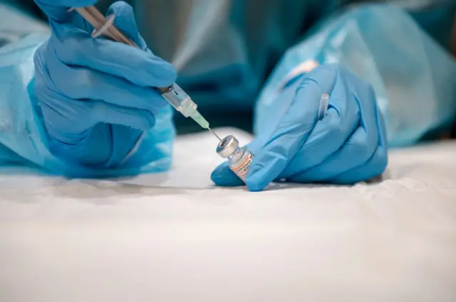 Generic photo of someone with gloves extracting vaccine from a vial.