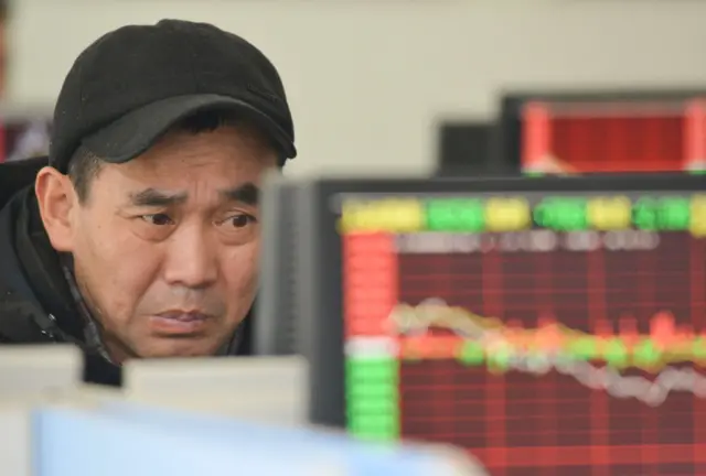 A Chinese investor checks a computer screen showing share prices at a securities brokerage.