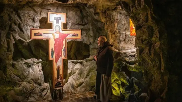 A monk looks at a crucifix.