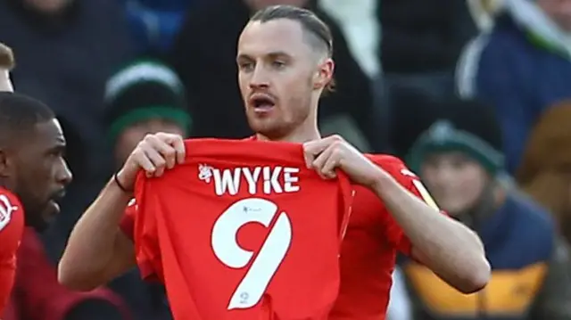 Will Keane holds up a Charlie Wyke shirt