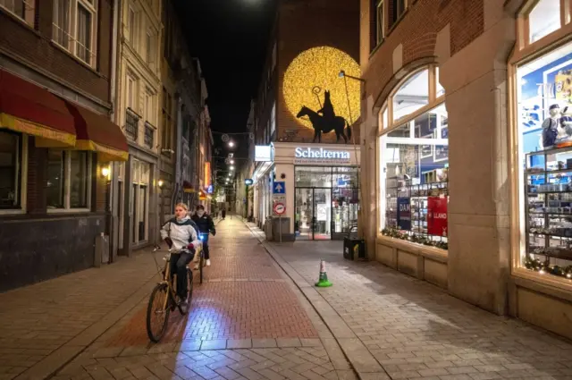 People riding their bicycles next to closed shops in Amsterdam, The Netherlands