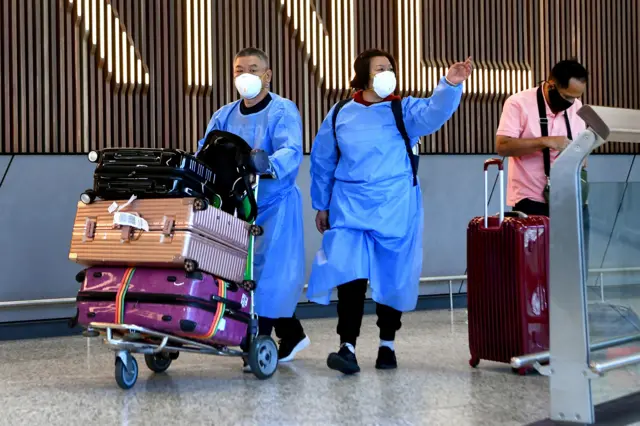 International travellers wearing personal protective equipment (PPE) arrive at Melbourne's Tullamarine Airport on November 29, 2021