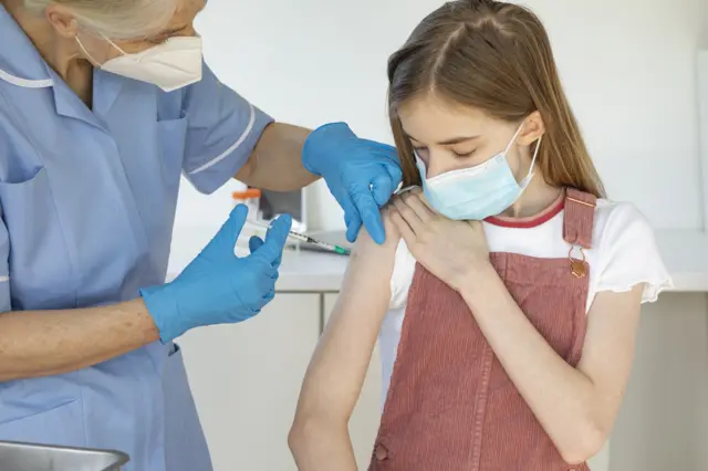 Teenage girl being given vaccine by a nurse