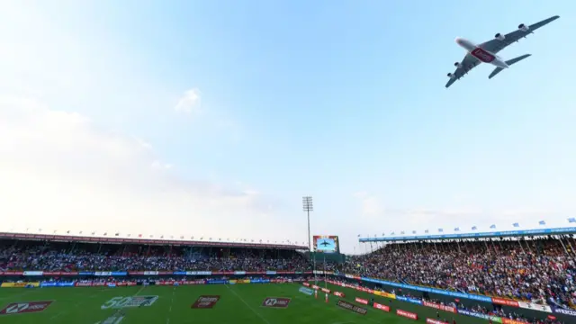 A plane flies over the World Rugby 7s in Dubai