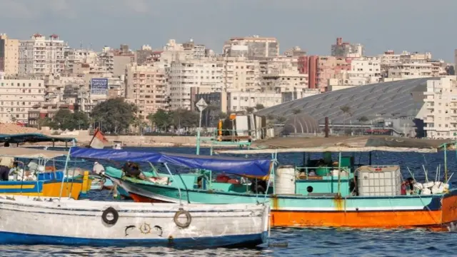 The Bibliotheca Alexandrina library is seen behind fishing boats in the harbour of Alexandria, Egypt (26 September 2021)