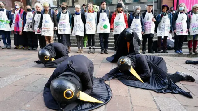 Protesters dressed as birds lying down