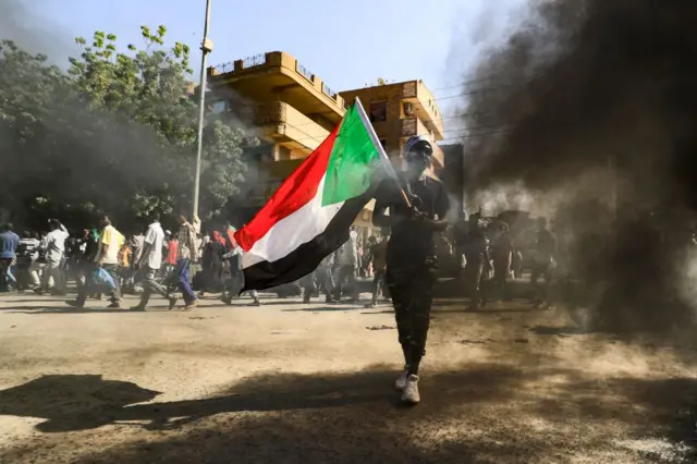 A man waves a Sudanese national flag as people gather for a demonstration in the centre of Sudan's capital Khartoum on 30 November while protesting against a deal that saw the civilian prime minister reinstated after the military coup in October.