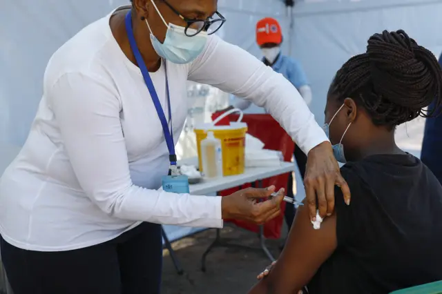 A healthcare worker administers the Johnson and Johnson vaccine to a woman outside a polling station in Laudium, Pretoria, on November 1, 2021,