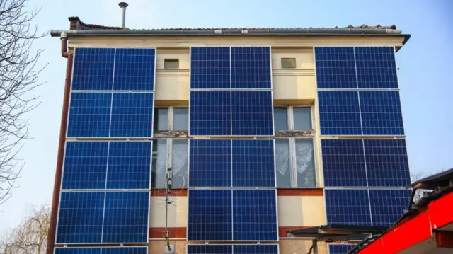 A number of solar collector panels are attached to the front wall of an old house in the centre of Krakow