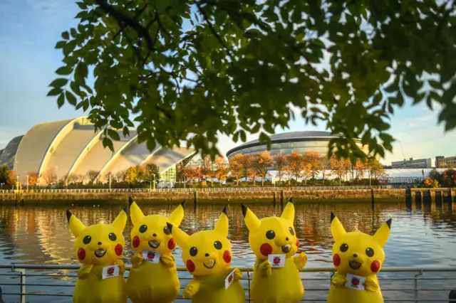 : Protesters dressed as Pikachu are seen holding signs reading Japan stop funding coal during a protest