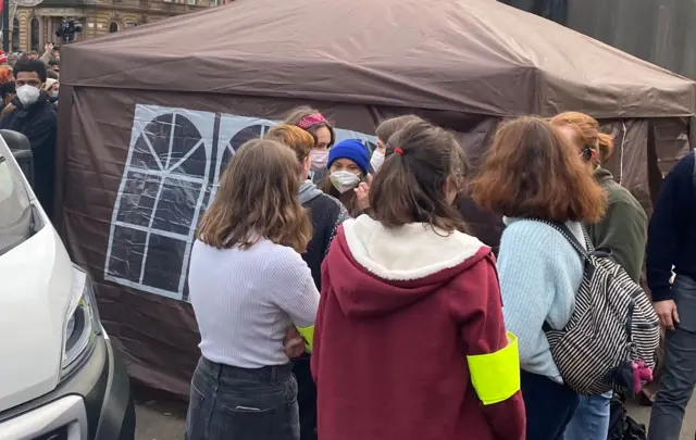 Greta Thunberg waits in a group near the main stage in George Square