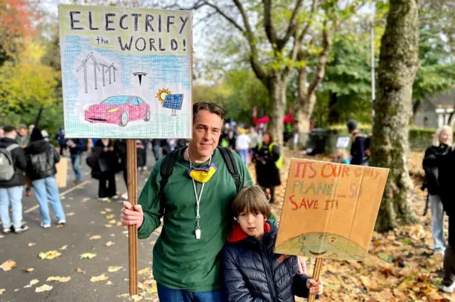 Patrick Klein and his son Philip hold up climate banners