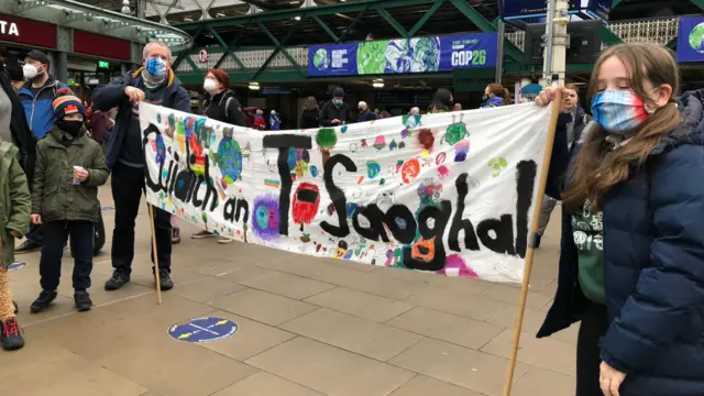 Young people unfurl a banner at Edinburgh's Waverley Station