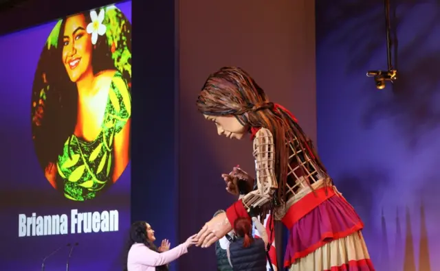 Activist Brianna Fruean approaches "Little Amal", a 3.5 metre tall puppet of a young Syrian refugee girl, during the UN Climate Change Conference