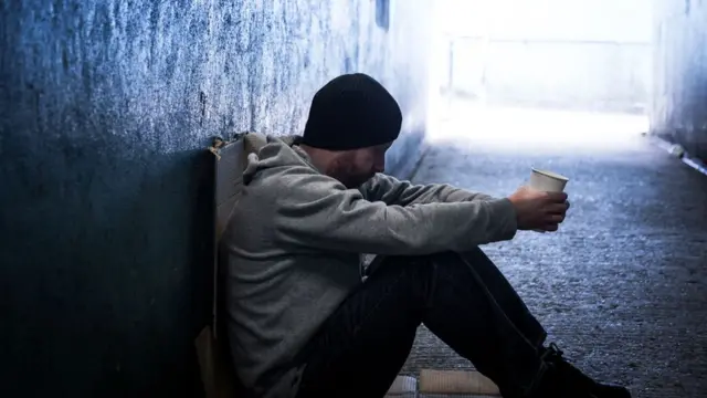 A stock image of a homeless man in an underpass