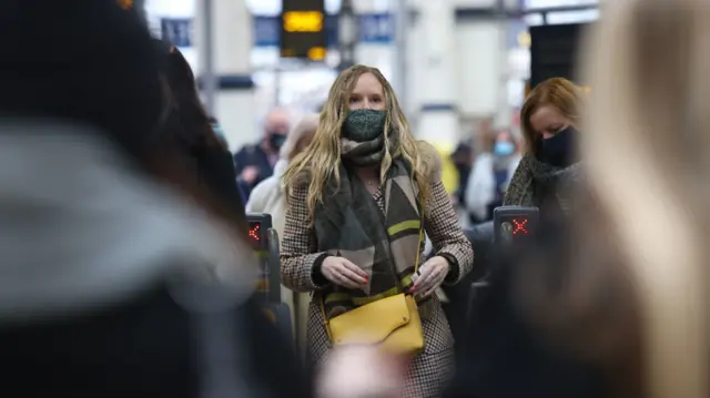 A woman going through a train ticket barrier