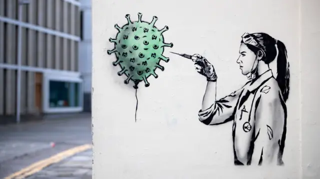 Graffiti of a vaccinator injecting a balloon that looks like the coronavirus