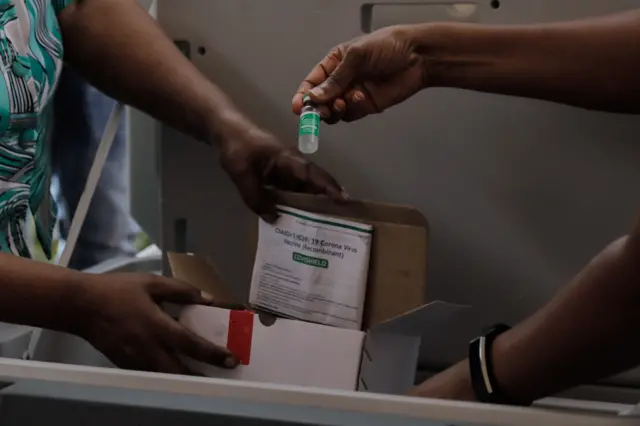 A staff member of Uganda's ministry of health holds a dose of the Oxford AstraZeneca Covid-19 vaccine at Mulago referral hospital in Kampala,