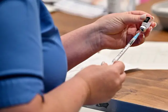 An NHS worker prepares to deliver a Covid vaccine