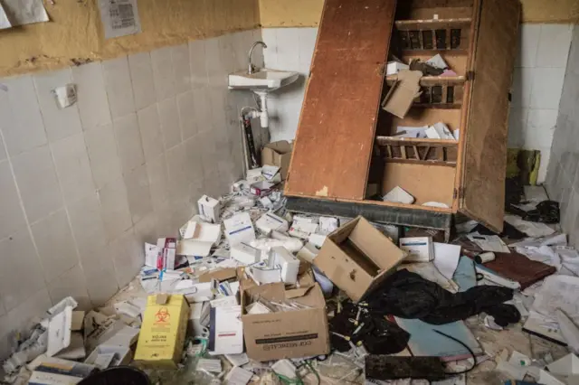 Photo of dilapidated hospital with medical equipment strewn across the ground