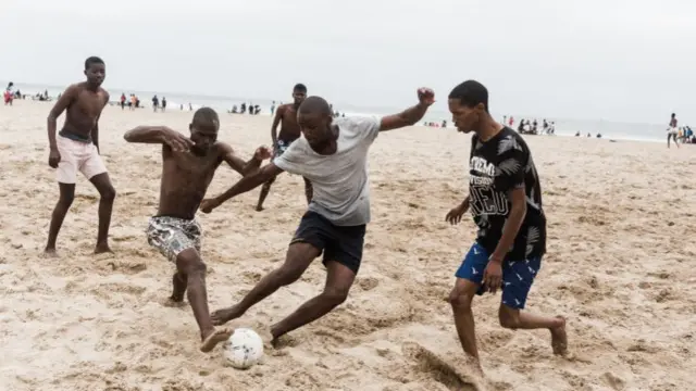 Beachgoers play football on the beach along Durban's Golden Mile beach front in Durban on December 16, 2021, amidst rising daily Covid-19 cases.