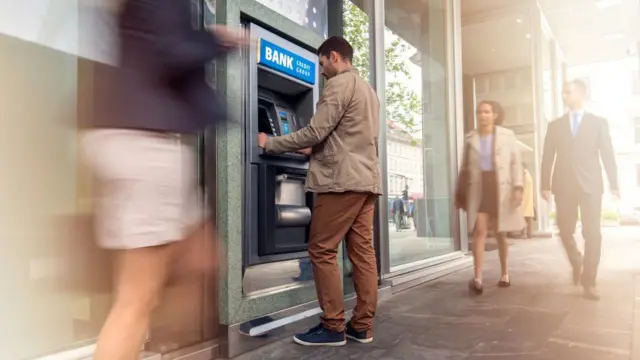 Man withdraws cash from a bank machine - stock shot