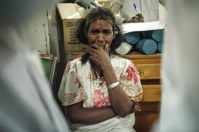 Tsigabu Gebretinsae, 45, holds her emotion as her daugher, a resident of Togoga, a village about 20km west of Mekele, received treatment for her lost arm at the Ayder referral hospital in Mekele, the capital of Tigray region, Ethiopia, on June 23, 2021, a day after a deadly airstrike on a market in Ethiopia's war-torn northern Tigray region, where a seven-month-old conflict surged again.