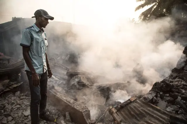 A man stand in front of a burnt down house in the PK5 district in Bangui on December 26, 2019, after clashes erupted when traders took up arms to oppose taxes levied by militia groups