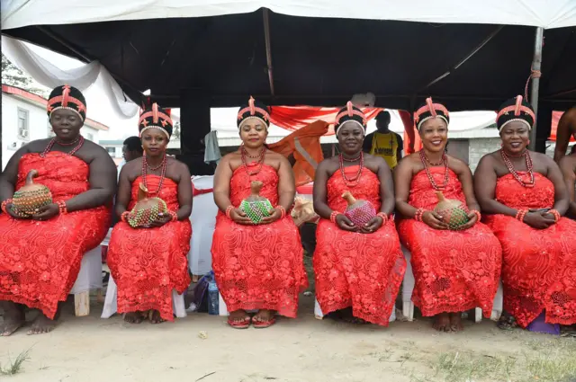 Women in red smiling for a photo. They are wearing traditional Nigerian clothes