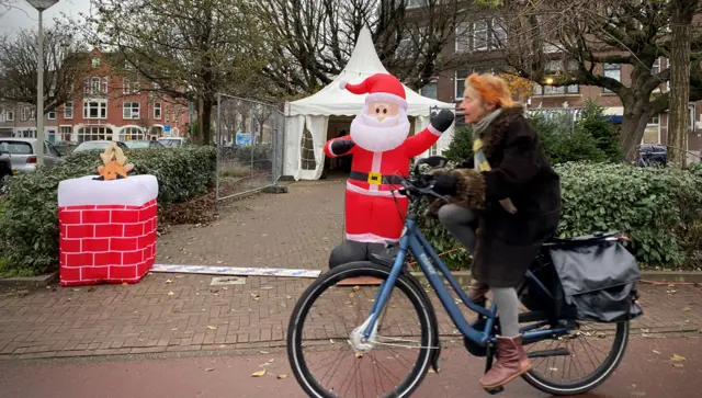 Woman cycling past inflatable santa