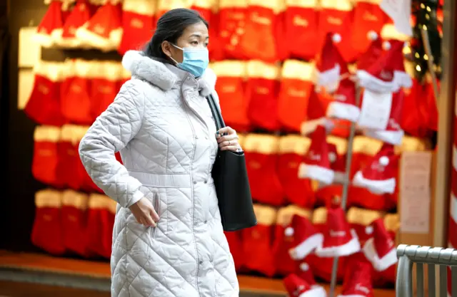 Woman in mask shopping next to Christmas decorations