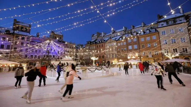 People go ice skating on an ice rink at the Old Town Square in Warsaw, Poland, 26 December 2021