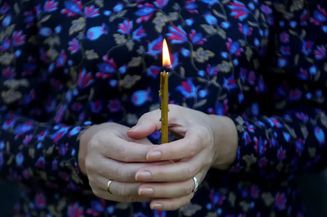 A woman holds a burning candle