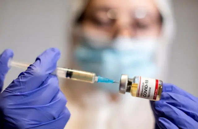 Lab worker with syringe and vaccine