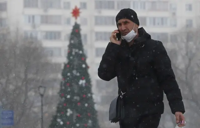 Man in Moscow walks past Christmas tree during the pandemic