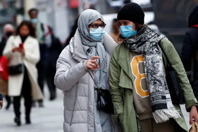 People wearing protective masks walk on a street, following the government"s restrictions imposed to contain the spread of coronavirus disease (COVID-19) in Brussels, Belgium, on 3 December 2021