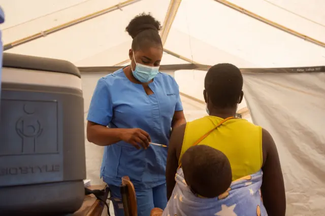 A nurse vaccinates a woman carrying a baby on her back at a hospital at Parirenyatwa group of hospitals on December 01, 2021 in Harare, Zimbabwe.