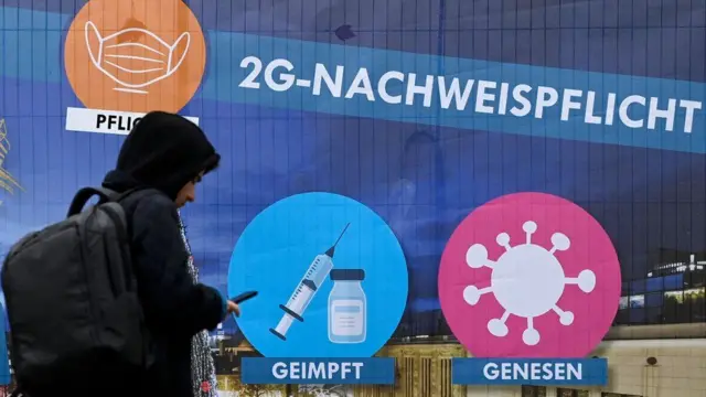 A man walks past a placard which indicates the so-called 2G rule (vaccinated or recovered from Covid-19) for the Christmas market in the city of Dortmund, Germany, on 1 December 2021