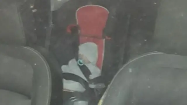 Realistic doll in baby seat inside car