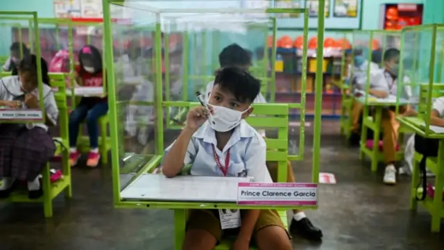 Schoolchildren sit under protective plastic barriers in a class in Pasay City, Metro Manila, Philippines. Photo: 6 December 2021