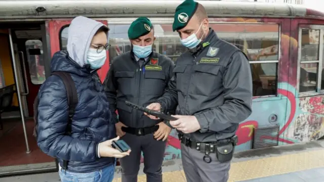 Officials check a Covid green pass of a man at a train station in Naples, Italy. Photo: 6 December 2021