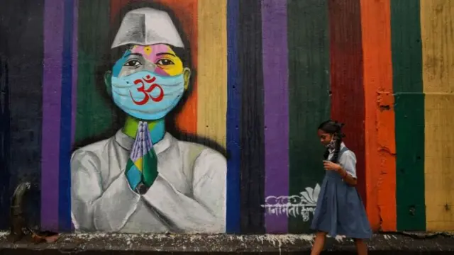 A schoolgirl walks past a Covid graffiti in Mumbai, India. Photo: December 2021