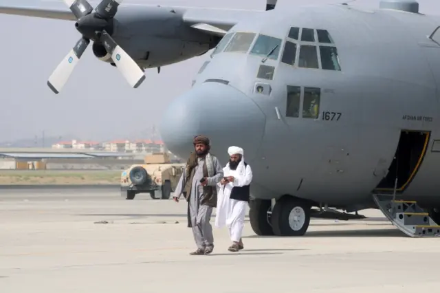 Taliban walk near an abandoned US military plane in Kabul on 31 August 2021