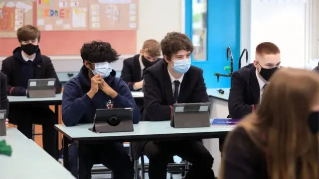 Children sitting in a classroom wearing face masks