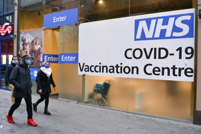 People walk past a vaccination centre in Stratford, east London