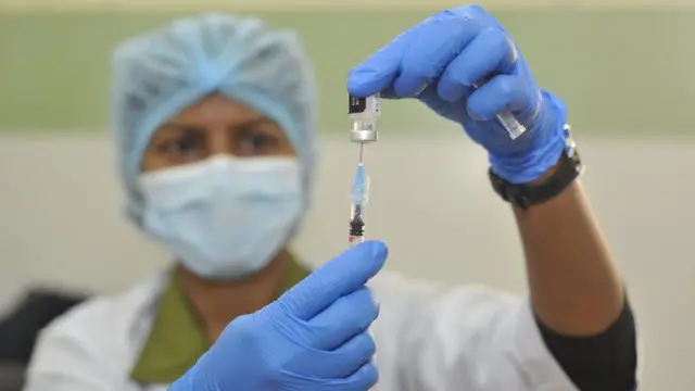 A medical worker holds a syringe