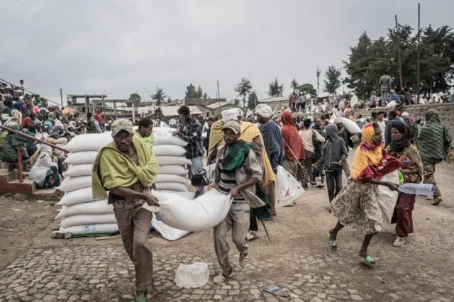 Men carry a sack of wheat during a food distribution by the World Food Programme (WFP) for internally displaced people (IDP) in Debark, 90 kilometres of the city of Gondar, Ethiopia, on September 15, 2021.