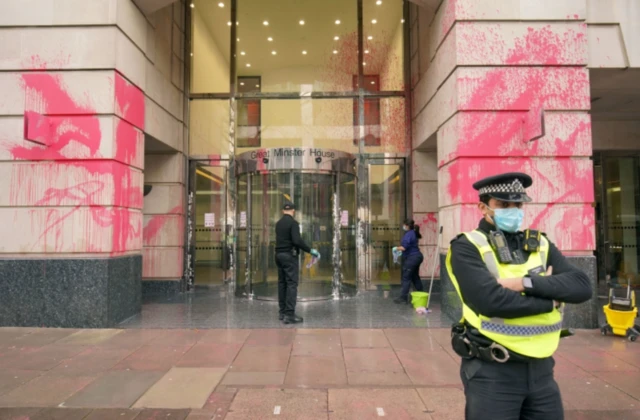 Police outside Department for Transport office, with pink paint