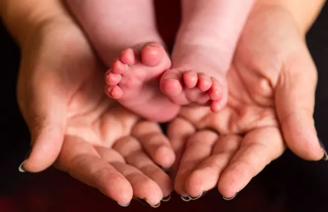 Baby feet in woman's hands